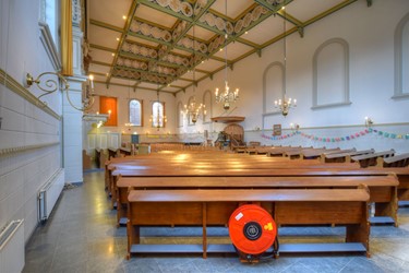<p>Overzicht van de huidige kerkruimte vanuit het noordoosten. De trekbalken van de hangwerken zijn geïntegreerd in het cassetteplafond, dat voorzien is van een verhoogd middengedeelte.</p>
